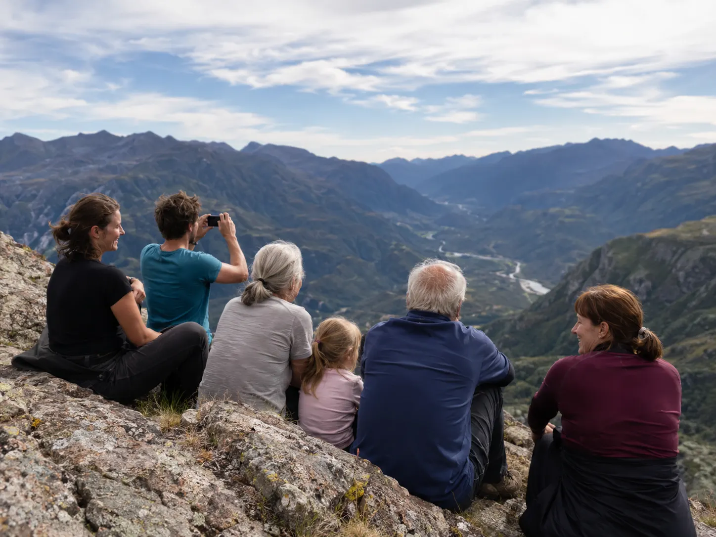 Familia de varias generaciones en una cima rocosa con vistas al valle